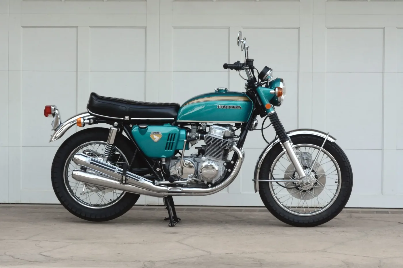 Restored turquoise Honda CB750 in front of a white wall
